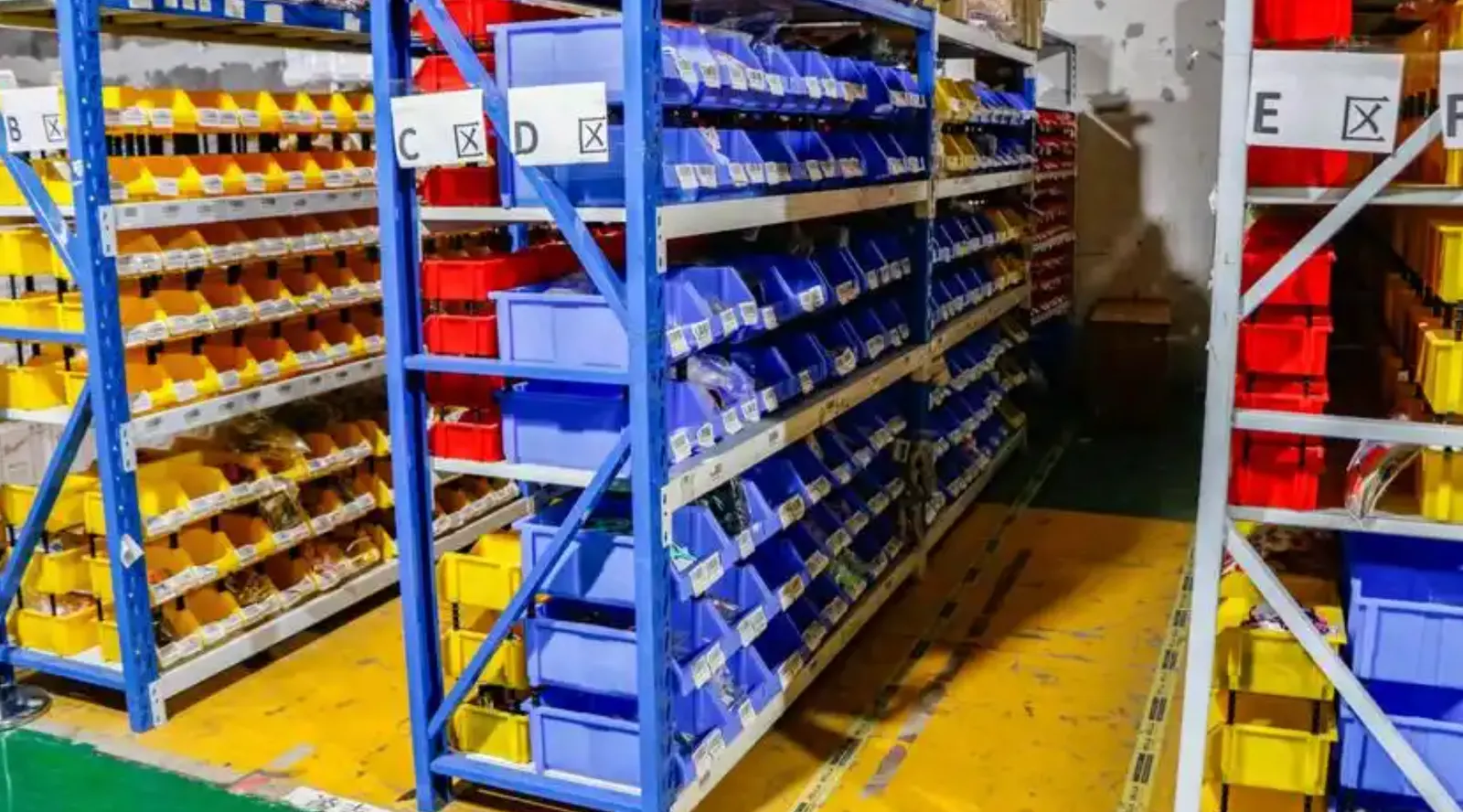 Color-coded storage bins arranged in labeled warehouse zones